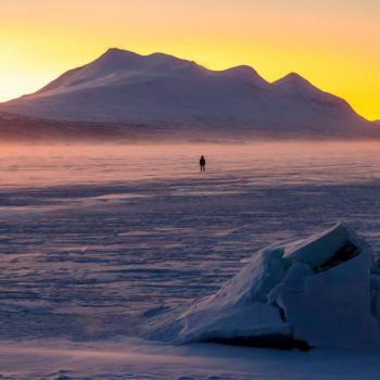 Personne regardant le coucher de soleil sur un lac de glace en Suède, photo prise durant le voyage Laponie par Renardo & Puffinou. ©Jean Navarro